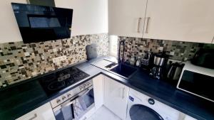 Il comprend une cuisine équipée d'un lave-linge, d'un évier et d'un four micro-ondes. dans l'établissement Cozy and Modern 1 Bedroom 3 room Apartment, à Wiesbaden 5 autres photos