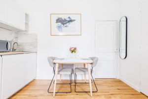 a white kitchen with a table and chairs at Cosy Studio Etoile Friedland - MOBILITY LEASE in Paris