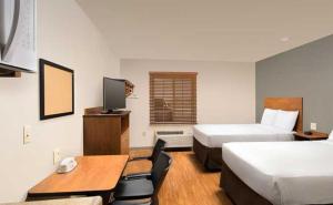 a hotel room with two beds and a desk at WoodSpring Suites Council Bluffs in Council Bluffs