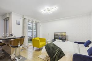 Habitación blanca con cama y silla amarilla en Chic apart with parking near Paris, en Rueil-Malmaison