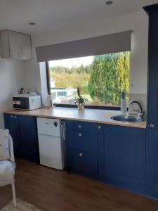 a blue kitchen with a sink and a window at The Hive at Seonaidbheag in Perth