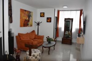 a living room with an orange couch and a table at ApartaHotel Modelia con Parqueadero in Bogotá