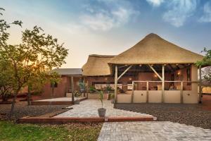 dom z dachem krytym strzechą i dziedzińcem w obiekcie The Nkhosi Livingstone Lodge and Spa w mieście Livingstone