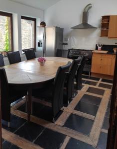 une cuisine avec une table en bois et des chaises noires dans l'établissement Granny Cottage., à Marchin
