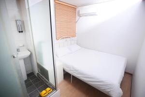 - une petite chambre avec un lit et une douche dans l'établissement All Stay Inn Seoul, à Séoul