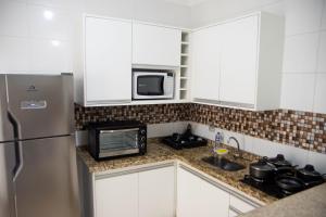 a kitchen with a stainless steel refrigerator and a microwave at Geovane Acomodação in Boituva