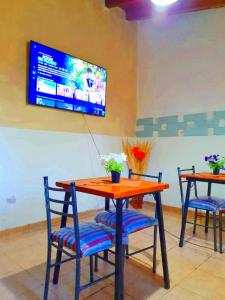een tafel en stoelen met een tv aan de muur bij BACANO hostel in Las Heras