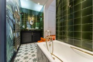 y baño con paredes de azulejos verdes y bañera. en Spacious seafront apartment: bold & beautiful, en Brighton & Hove