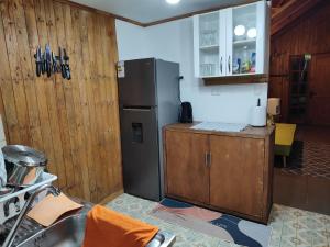 a kitchen with a refrigerator and a wooden wall at Cabaña Uka Moana in Hanga Roa