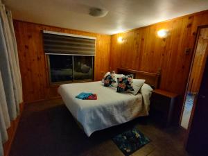 Un dormitorio con una cama con paredes de madera y una ventana en Cabaña Uka Moana, en Hanga Roa