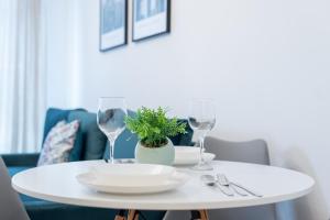 a white table with a plate and two wine glasses at Pure Rental Apartments in Wrocław