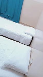 3 almohadas blancas apiladas en una cama en M&M للشقق الفندقية en Majān