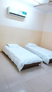 2 camas en una habitación de hospital con TV en la pared en M&M للشقق الفندقية, en Majān