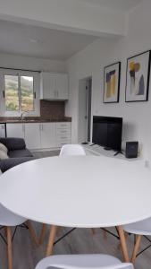 sala de estar blanca con mesa y cocina en Pico dos Anjos, en Porto Moniz