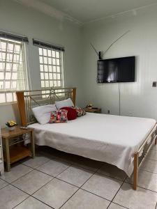um quarto com uma cama grande e uma televisão na parede em Casa 3 suítes no centro de Cuiabá em Cuiabá
