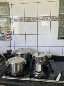 duas panelas e frigideiras num fogão numa cozinha em Casa 3 suítes no centro de Cuiabá em Cuiabá