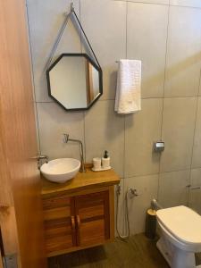 y baño con lavabo, aseo y espejo. en pousada solar da canastra en Delfinópolis