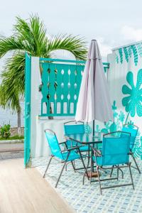 eine Terrasse mit einem Tisch, Stühlen und einem Sonnenschirm in der Unterkunft Hotel Casa Turquesa in Flores