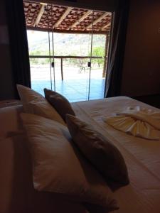 a bed with pillows in a room with a window at pousada solar da canastra in Delfinópolis