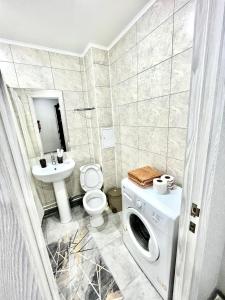 Un baño con lavadora y lavabo. en 1 комнатная квартира посуточно, en Uralsk