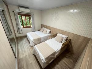 Habitación con 2 camas y ventana en Casa mais Central de Gramado, en Gramado