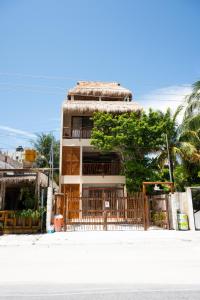 a building with a fence and a tree in front of it at Yax Kiin Casa Boutique in Puerto Morelos