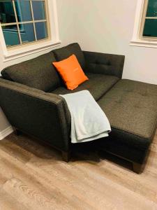 ein schwarzes Sofa mit orangefarbenem Kissen drauf in der Unterkunft Casita Blanca- Close To Downtown in Waco