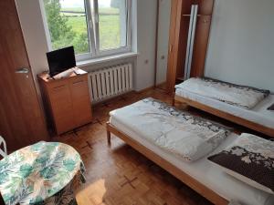 にあるAgroturystyka LUCYNAのベッド2台、デスク、窓が備わる客室です。