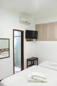 a room with a bed and a mirror and a tv at Hotel Metropolitano in Coronel Fabriciano