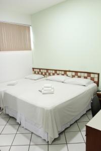 a large white bed with two white towels on it at Hotel Metropolitano in Coronel Fabriciano