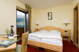 a bedroom with a bed and a desk and a window at Hotel del Bosco in Livigno