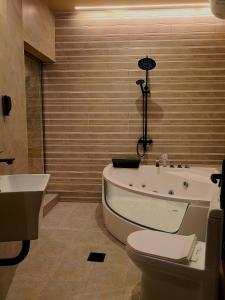 a bathroom with a tub and a toilet and a sink at Alaqur View Inn نزل واجهة العقر in Nizwa