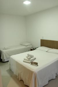 duas camas com lençóis brancos e toalhas numa mesa em Hotel Metropolitano em Coronel Fabriciano