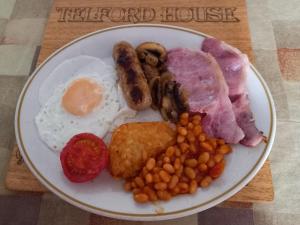 um prato de alimentos com ovos, bacon, feijão e carne em Telford House em Milton Keynes