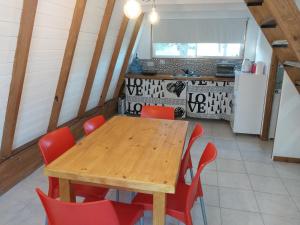 cocina con mesa de madera y sillas rojas en Cabaña alpina Las Lomas en Monte Hermoso