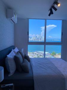 sypialnia z łóżkiem i dużym oknem w obiekcie Apartamento con piscina infinita frente al mar en Avenida Balboa PH The Sand w Panamie