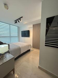 um quarto com uma cama e uma televisão na parede em Apartamento con piscina infinita frente al mar en Avenida Balboa PH The Sand em Cidade do Panamá