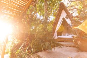uma cama numa tenda debaixo de uma árvore em Hostel Da Vila Ilhabela em Ilhabela