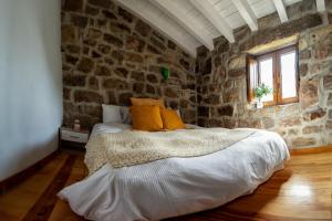 1 dormitorio con 1 cama en una pared de piedra en Cabaña Pasiega Las Suertes en San Pedro del Romeral