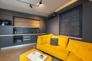 uma sala de estar com um sofá amarelo e uma mesa em TOPAZ Beachfront Apartment em Varna City