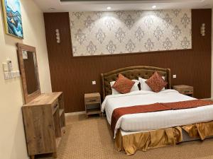 una camera con un grande letto e uno specchio di فندق جارة الغيم للاجنحة الفندقية a Fayfāʼ
