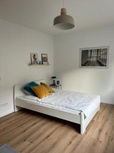 Cama blanca en habitación con suelo de madera en Kleines und feines Apartment in Zentrum en Mannheim