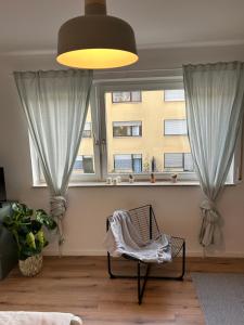 a living room with a chair and two windows at Kleines und feines Apartment in Zentrum in Mannheim