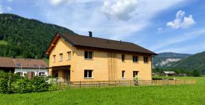 a large wooden house in a field with mountains at 751Pelzrain in Bezau