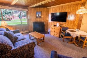ein Wohnzimmer mit einem Sofa, einem TV und einem Tisch in der Unterkunft Castle Mountain Lodge in Estes Park