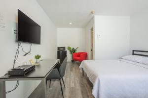 Habitación de hotel con cama y escritorio con TV. en Motel Champlain, en Brossard