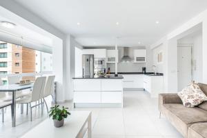 een witte keuken en een woonkamer met een bank en een tafel bij Versalles 732 Apartment Levante-Rincon Loix Area in Benidorm