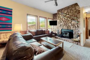 uma sala de estar com um sofá de couro e uma lareira de pedra em Gold Creek 208 em Angel Fire