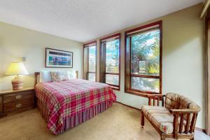 um quarto com uma cama, uma cadeira e janelas em Gold Creek 208 em Angel Fire