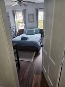 1 dormitorio con 1 cama con almohadas azules y ventilador de techo en Street side studio apartment en Mánchester